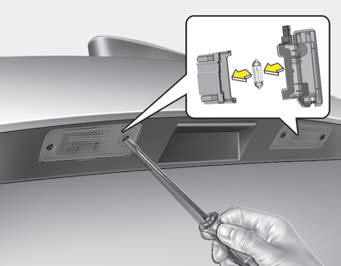 Kia Carnival: License plate light bulb replacement. 1. Loosen the lens retaining screws with a phillips head screwdriver.